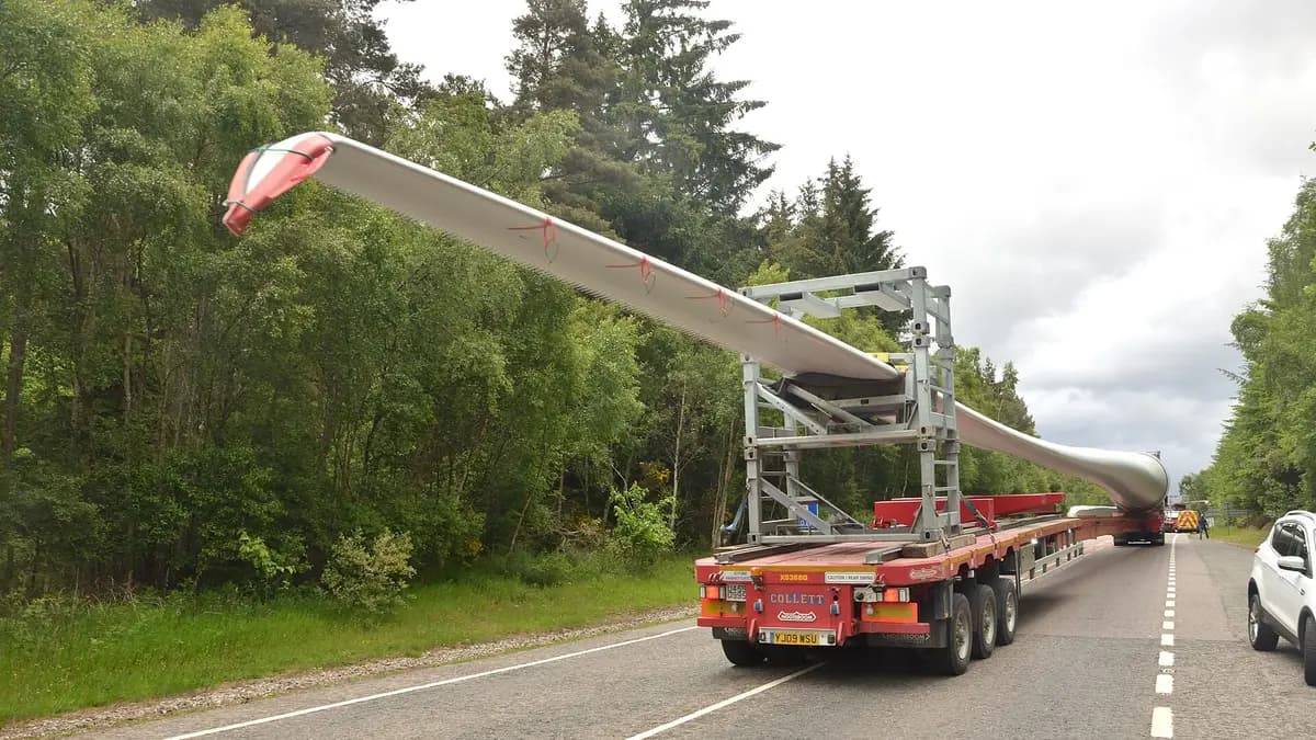 Pala de aerogenerador transportada en un remolque especial que la mantiene inclinada sobre una carretera